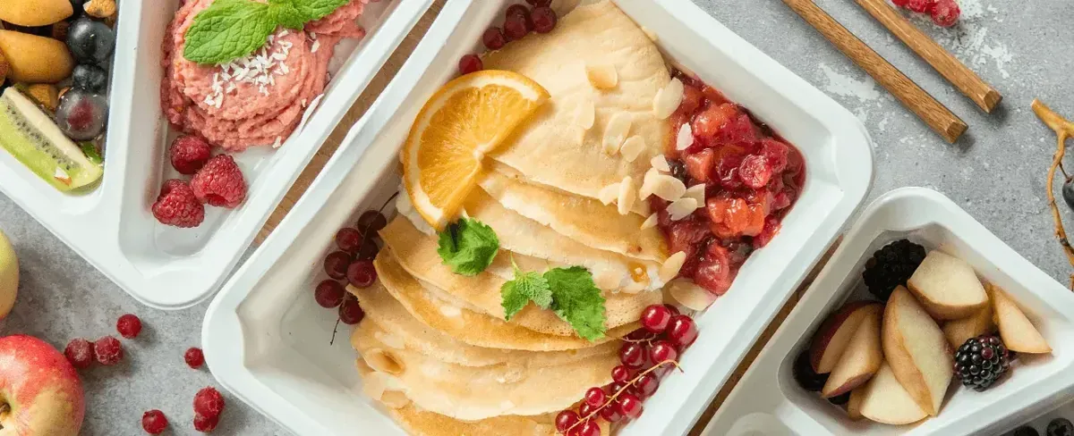 Pudełka cateringu z naleśnikami, owocami i przekąskami